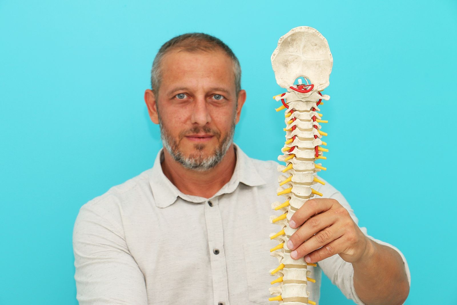 Alexandre Zuppo a segurar um modelo de coluna vertebral no consultório